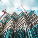A high-angle view of a modern building under construction with red cranes, representing the professional scale and architectural expertise of home extension builders Harrow.