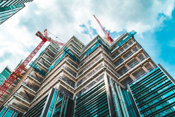 A high-angle view of a modern building under construction with red cranes, representing the professional scale and architectural expertise of home extension builders Harrow.