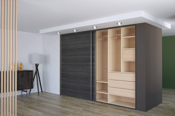 A modern floor-to-ceiling built-in wardrobe with dark grey wood-effect sliding doors and custom light-wood interior shelving, illustrating high-quality bespoke furniture London.
