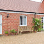 A side-view of a newly completed red-brick single-storey house addition with white timber doors and windows, representing a project used to estimate price in a home extension cost calculator UK.