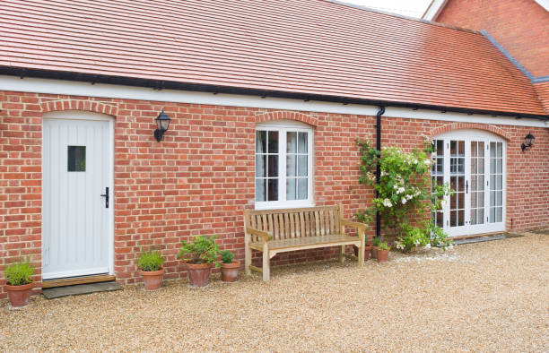 A side-view of a newly completed red-brick single-storey house addition with white timber doors and windows, representing a project used to estimate price in a home extension cost calculator UK.
