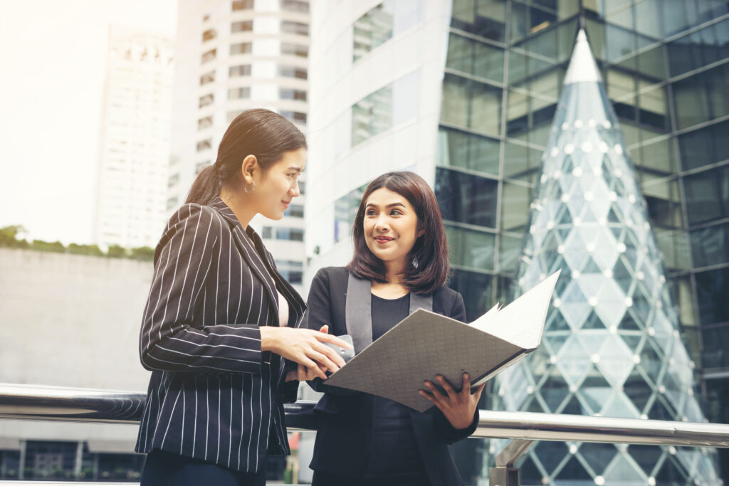 businesswomen-discussing-paperwork-together-against-railing-business-people-concept_3_optimized_2000