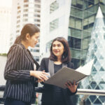 businesswomen-discussing-paperwork-together-against-railing-business-people-concept_3_optimized_2000