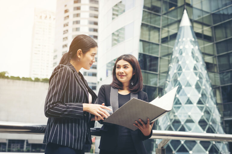 businesswomen-discussing-paperwork-together-against-railing-business-people-concept_3_optimized_2000