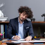 front-view-young-businessman-sitting-desk-writing-something (1) (1)