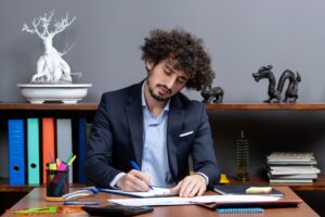 front-view-young-businessman-sitting-desk-writing-something (1) (1)