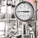 Hydraulic fluid pressure indicator. White dial. Abstract industrial background.