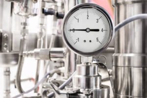 Hydraulic fluid pressure indicator. White dial. Abstract industrial background.