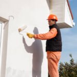construction worker is painting a wall with a roller