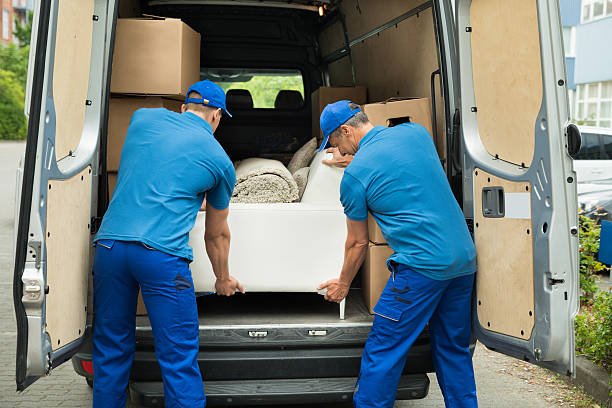 Two Male Workers In Blue Uniform Adjusting Sofa In Truck